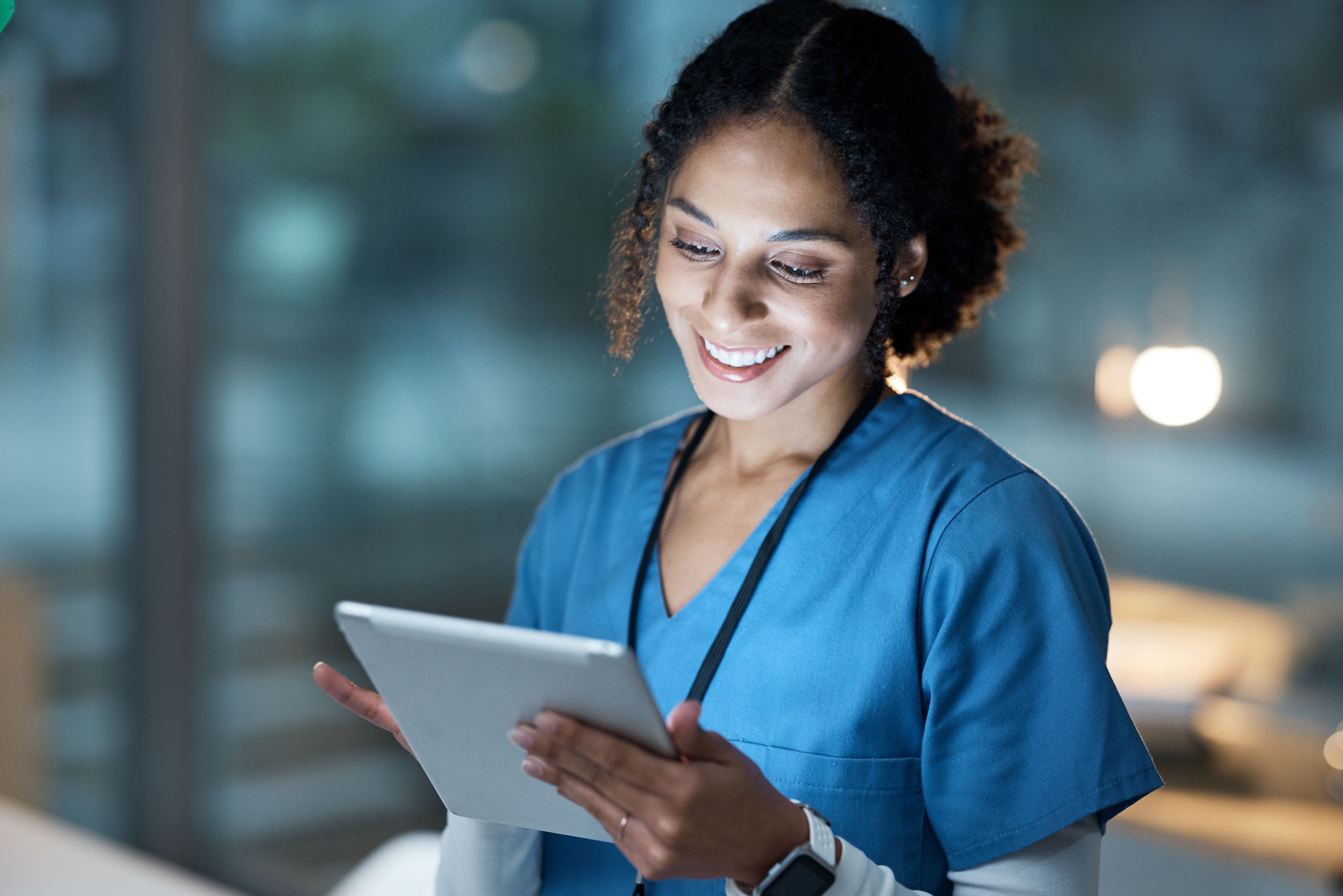 Nurse in scrubs smiling in a hospital corridor